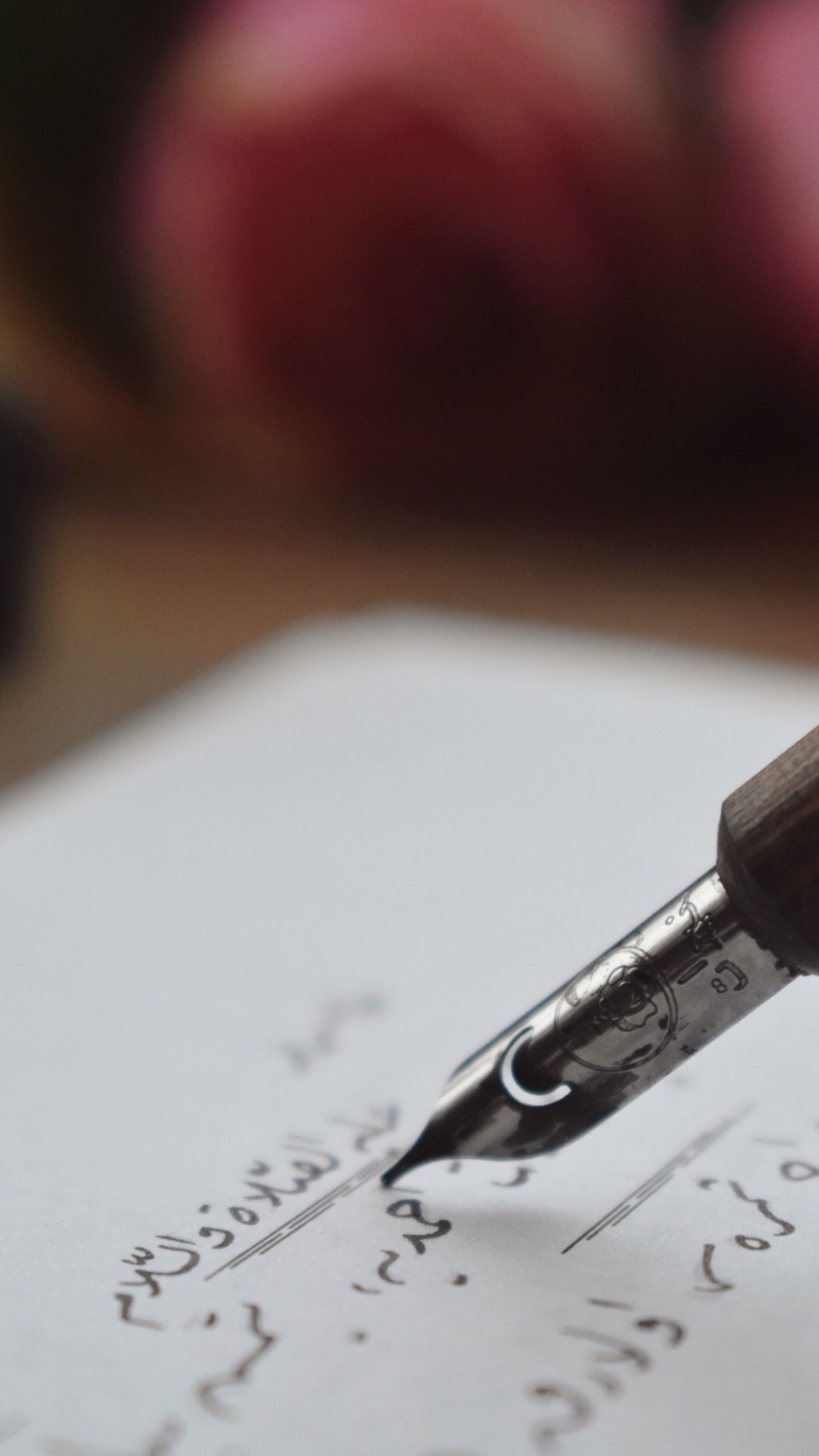 Close-up of a fountain pen writing elegant calligraphy on paper.